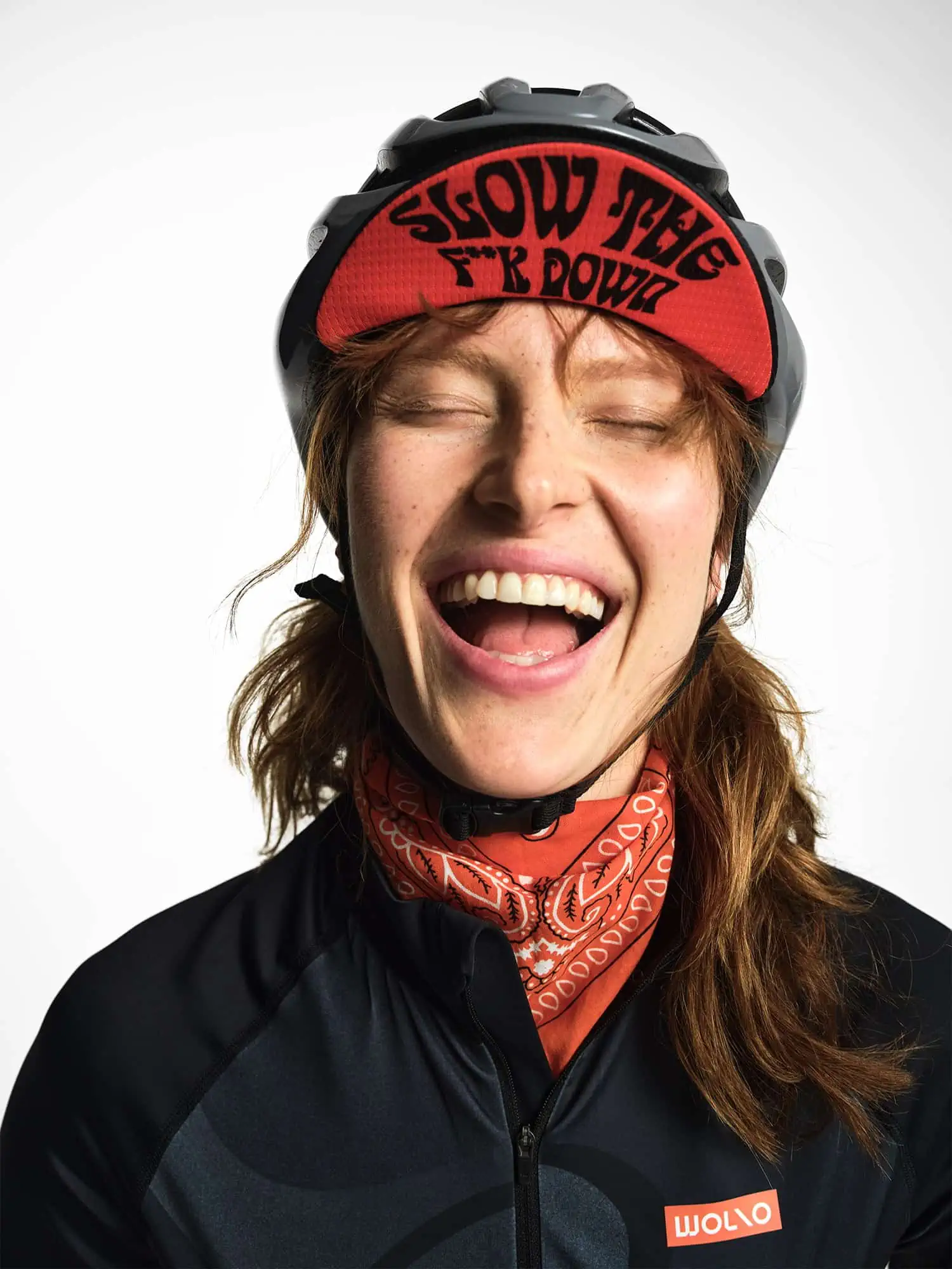 Uśmiechnięta kobieta w kasku, czapeczce rowerowej i koszulce rowerowej Wolno